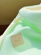 Light green fabric with a beige label on a blurred background