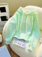 Light green hoodie on a white chair with a magazine underneath