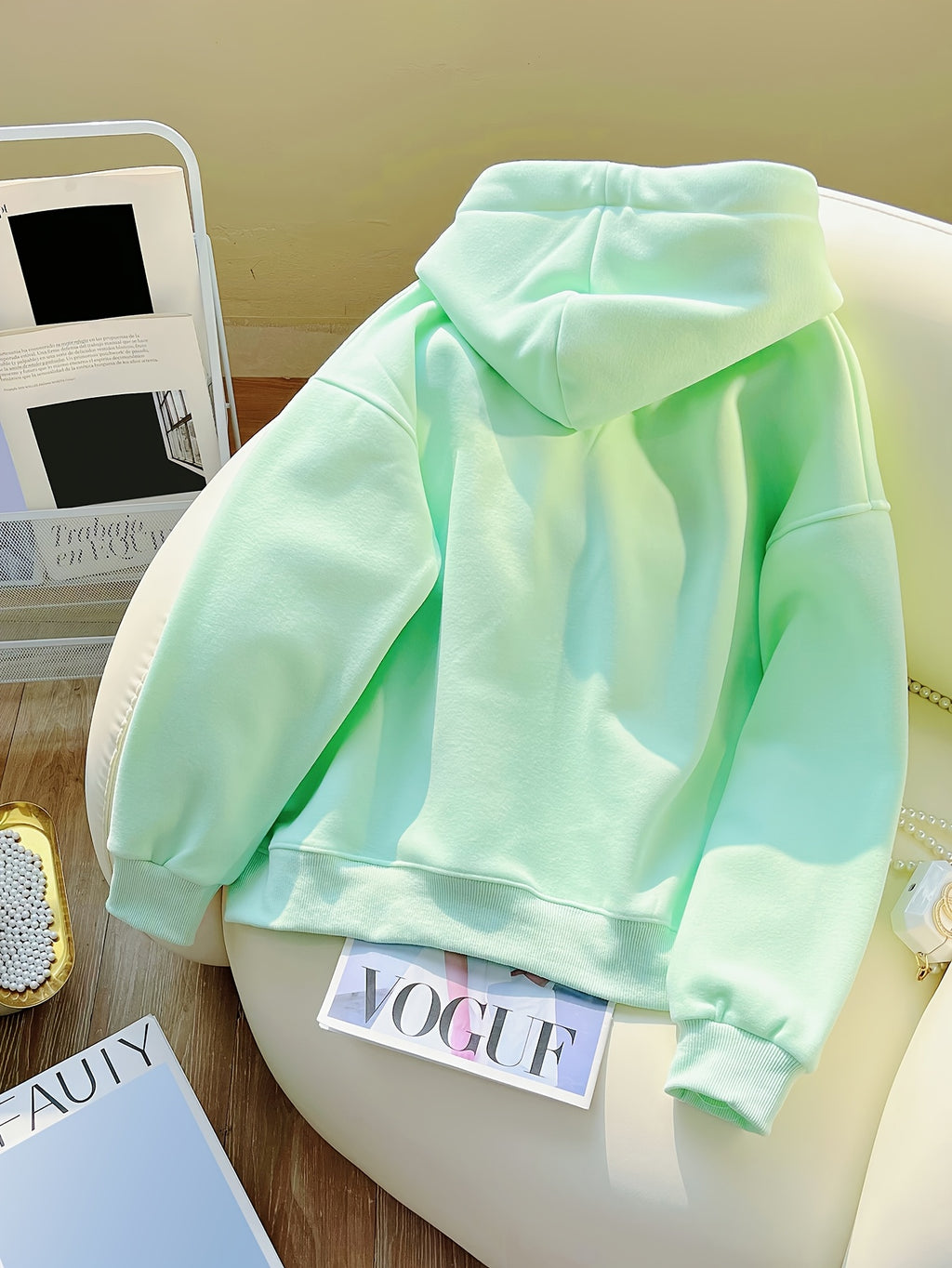 Light green hoodie on a chair with a magazine underneath
