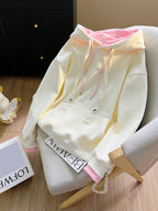 White hoodie with pink accents on a chair next to a book titled 'LOFWE'.