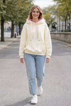 Woman wearing a light-colored hoodie and jeans walking on a street.