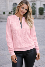 Woman wearing a pink cable knit sweater with a zipper outdoors.