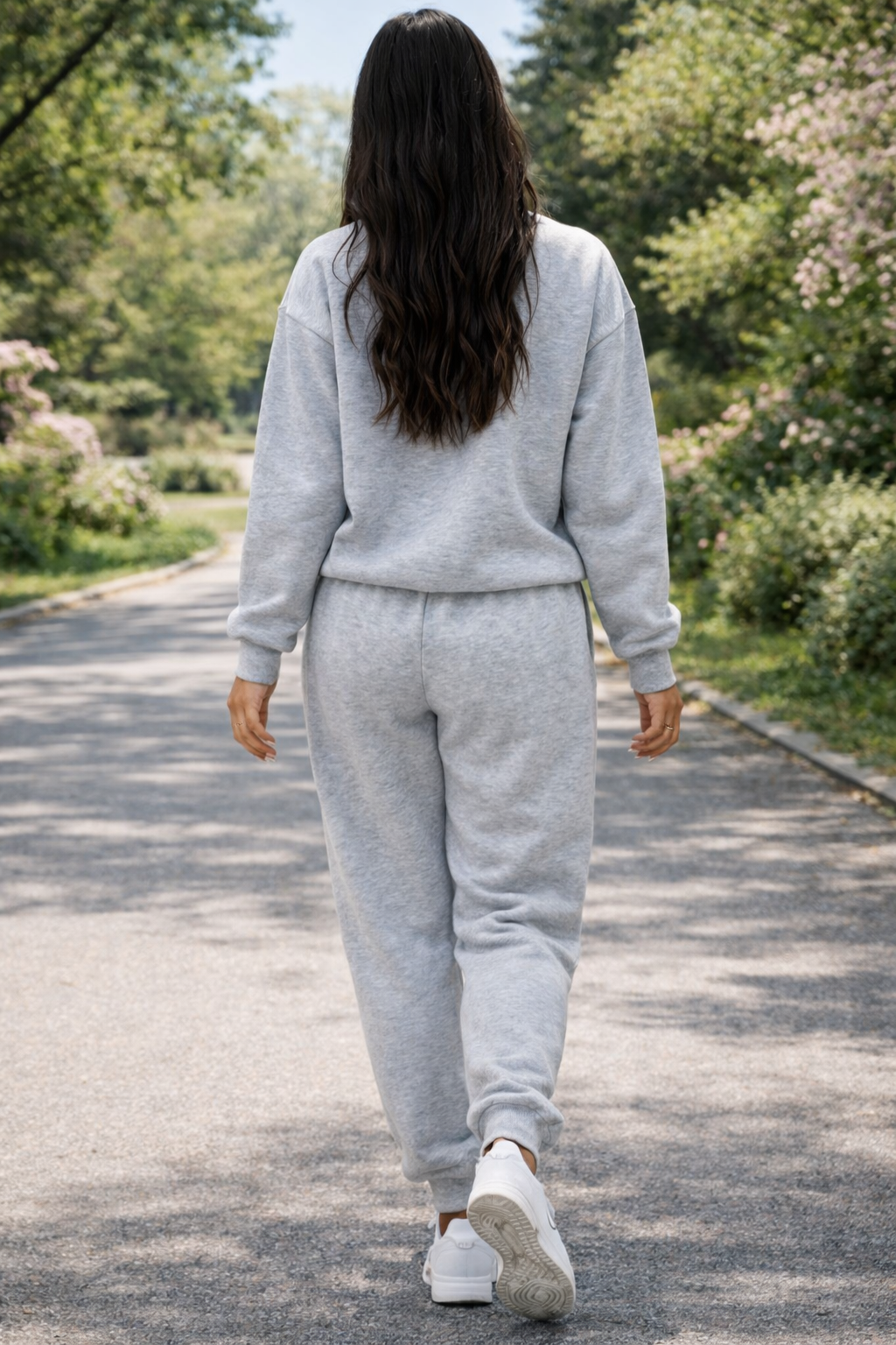 Person wearing a gray tracksuit walking on a path in a park.