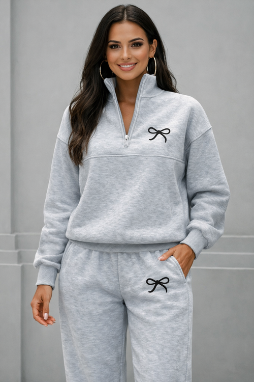 Woman wearing a gray tracksuit with a bow design on a plain background
