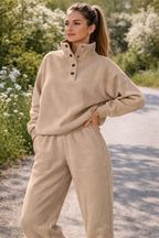 Woman wearing a beige outfit standing on a path with greenery around