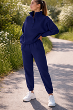 Woman in a blue tracksuit standing on a path with greenery around
