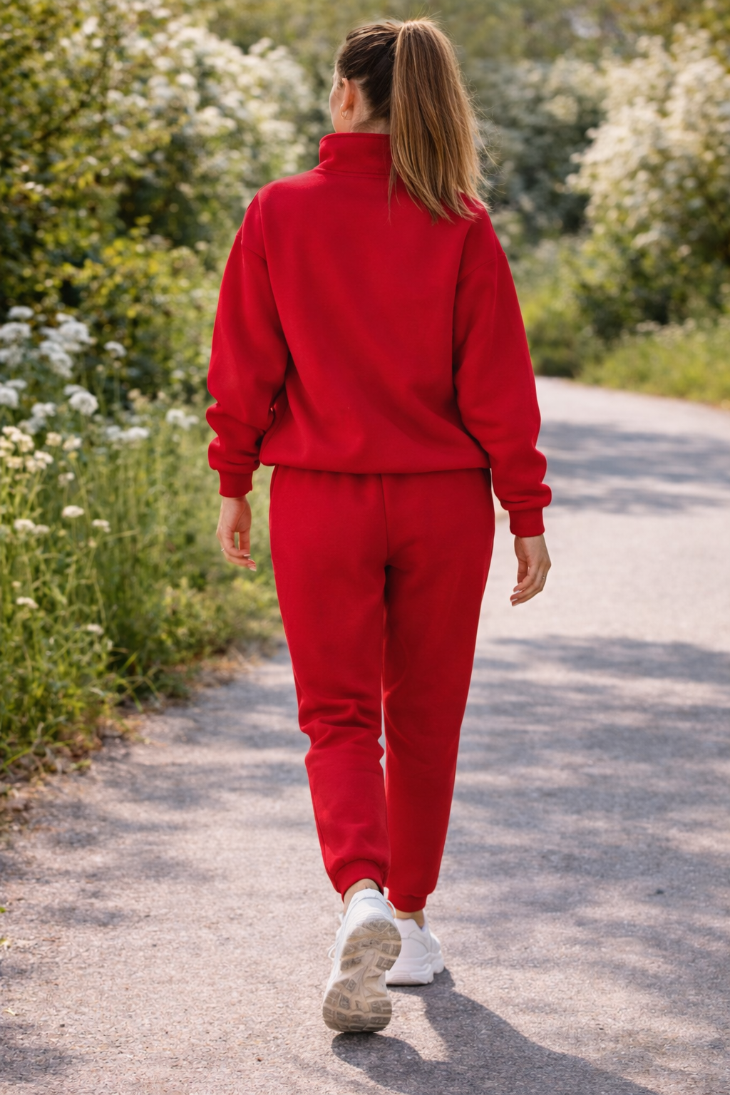 Person wearing a red tracksuit walking on a path surrounded by greenery
