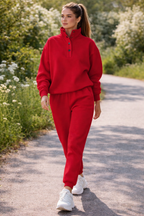 Woman in a red tracksuit walking on a path with greenery and flowers in the background