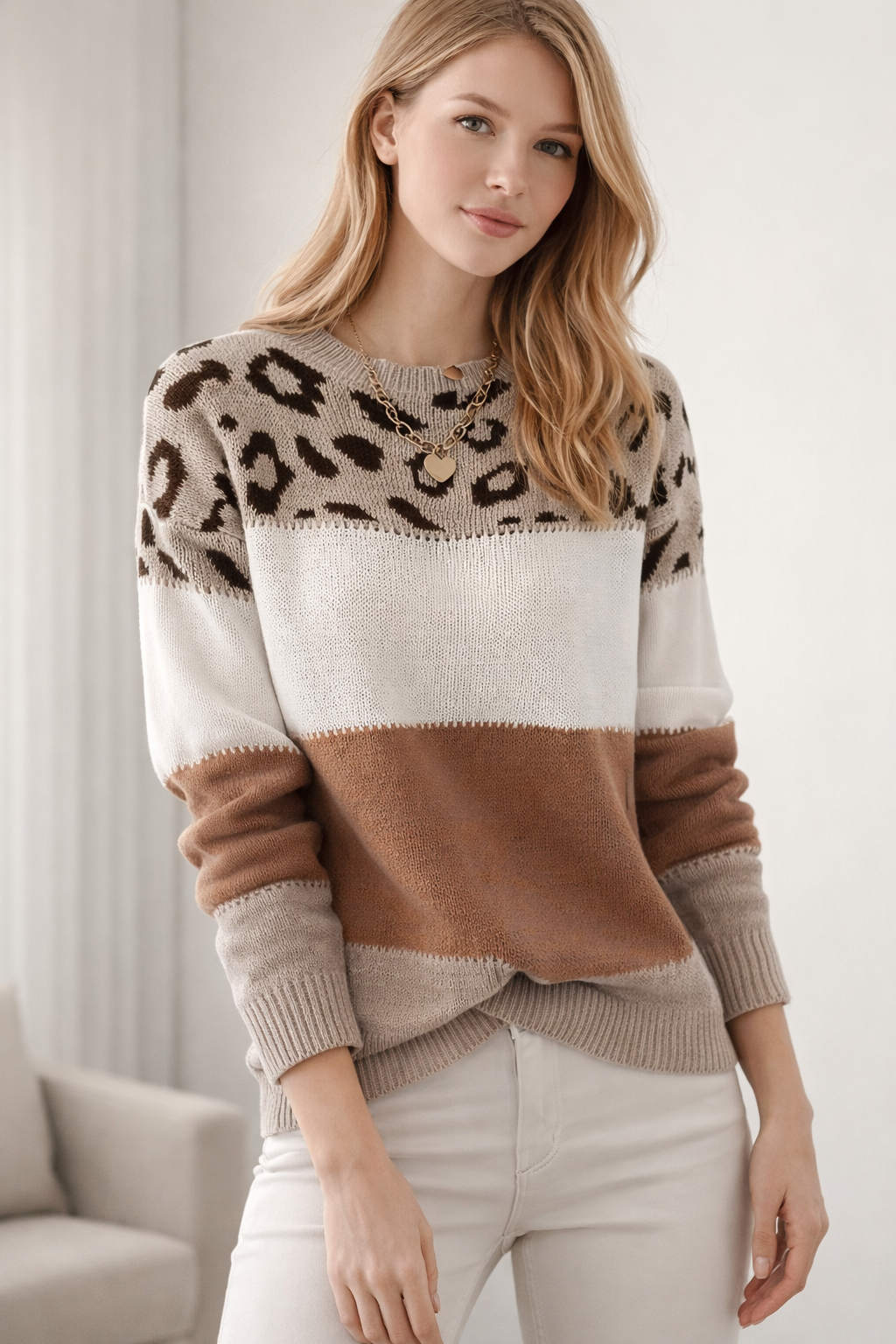 Woman wearing a leopard print and color-blocked sweater with white pants against a neutral background