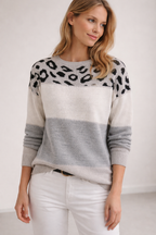 Woman wearing a sweater with leopard print and color-block design on a plain background