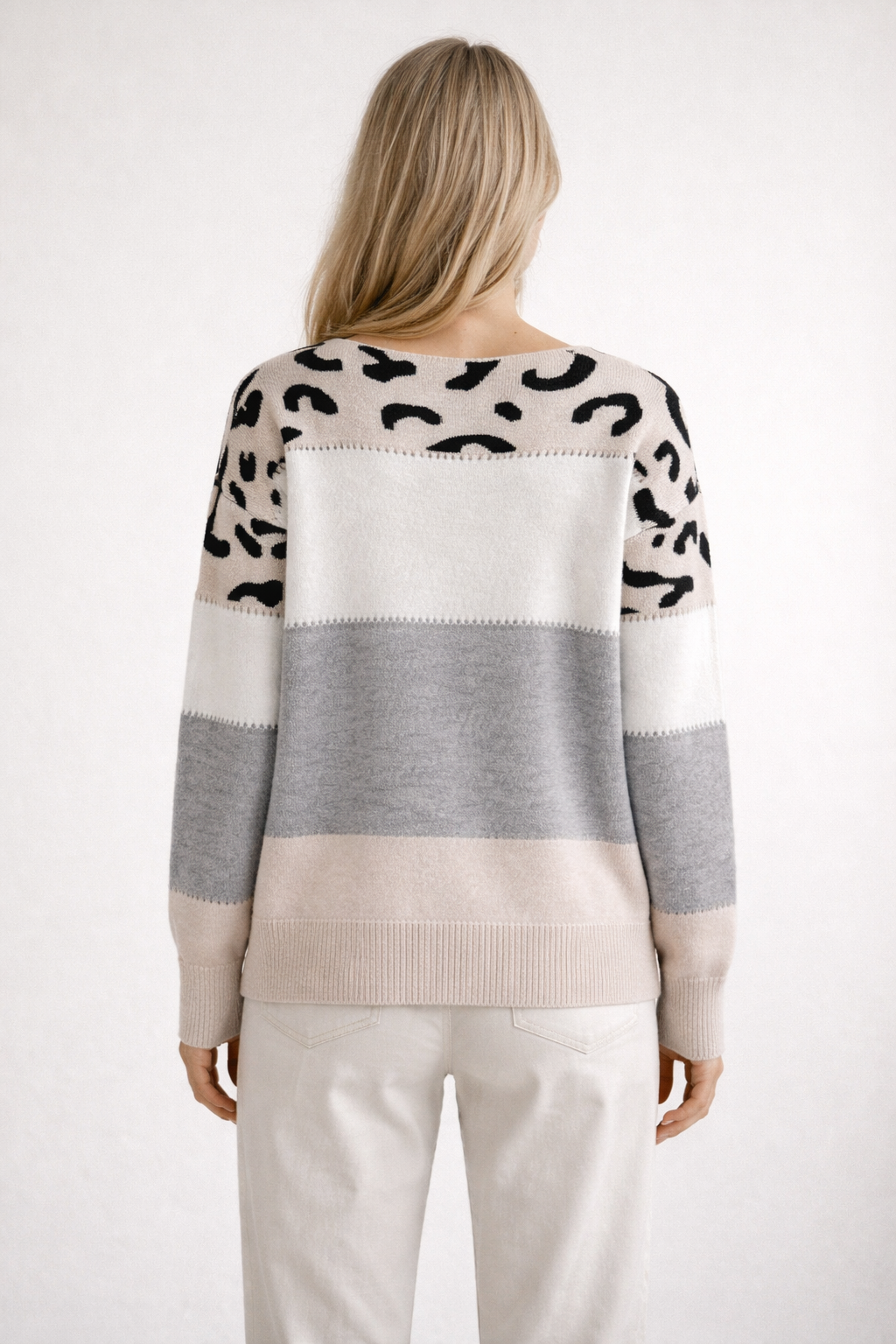 Person wearing a patterned sweater with color-block design on a white background