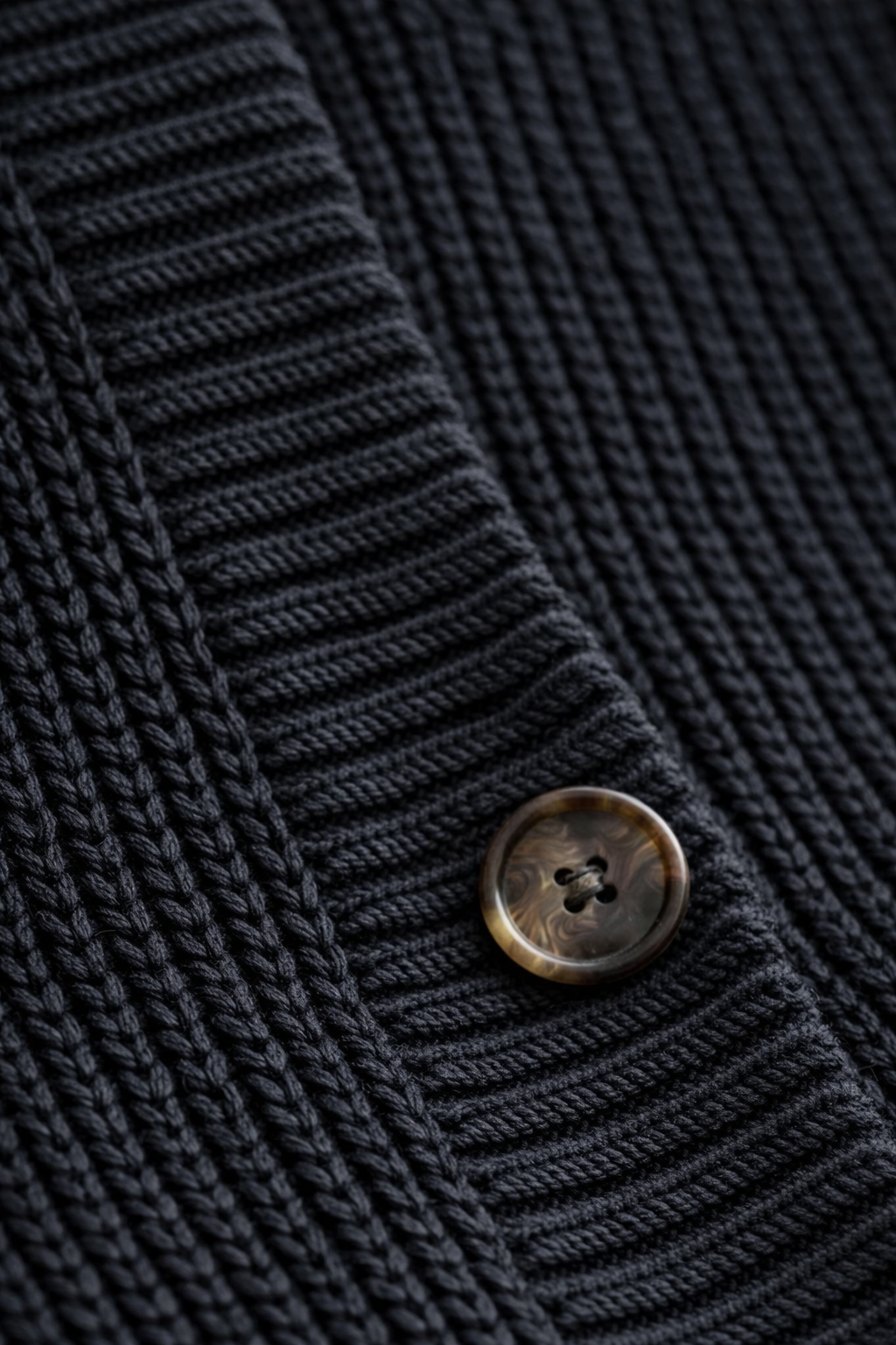 Close-up of a dark blue knitted fabric with a button