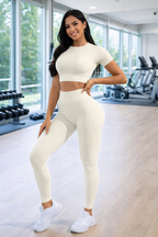 Woman in a white athletic outfit posing in a gym.