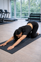 Woman stretching on a mat in a gym setting