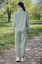 Person wearing a light green tracksuit walking on a path in a park.